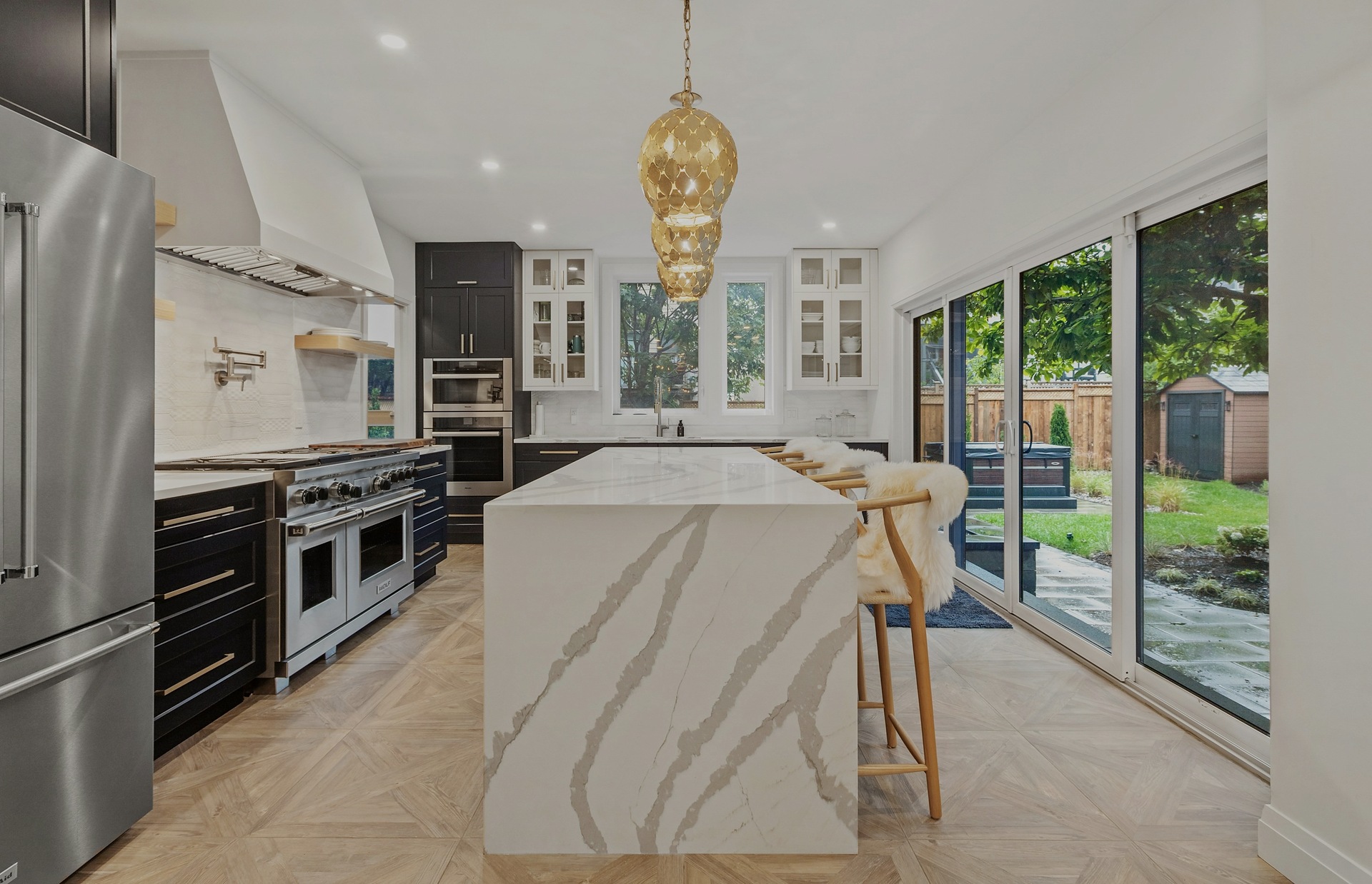 A luxury kitchen with a marble waterfall island and brass pendant lighting